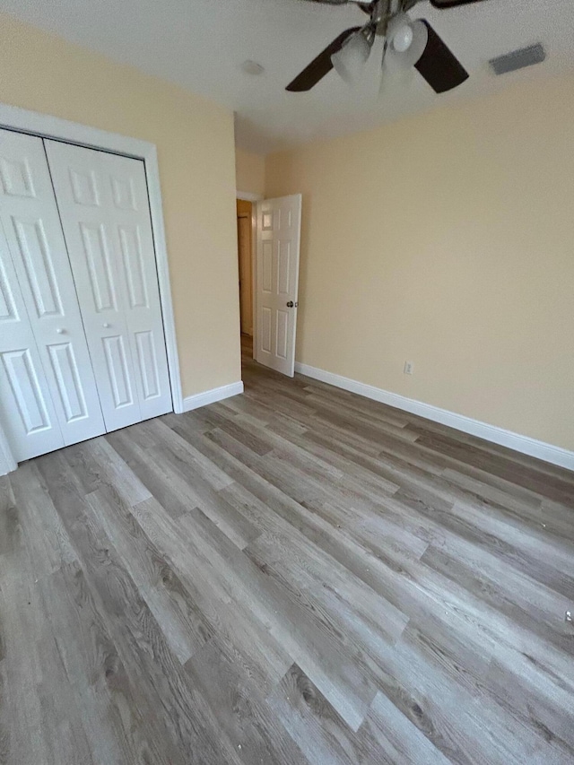 unfurnished bedroom featuring ceiling fan, light hardwood / wood-style flooring, and a closet