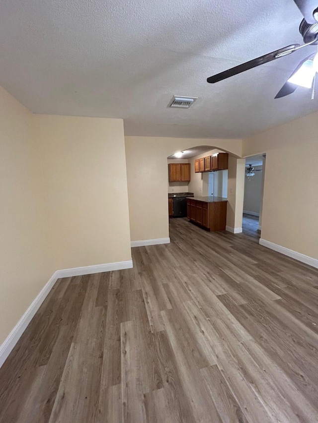 unfurnished living room with wood-type flooring, a textured ceiling, and ceiling fan