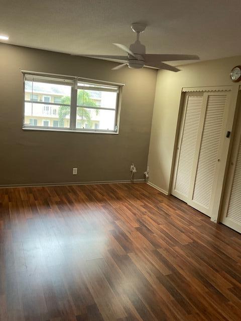 unfurnished bedroom with a closet, multiple windows, dark wood-type flooring, and ceiling fan