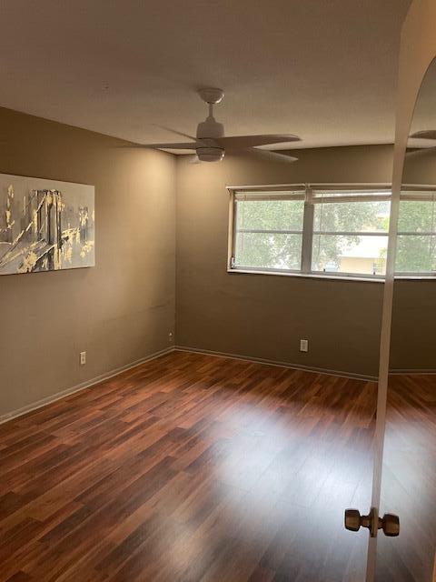 spare room featuring ceiling fan and dark wood-type flooring