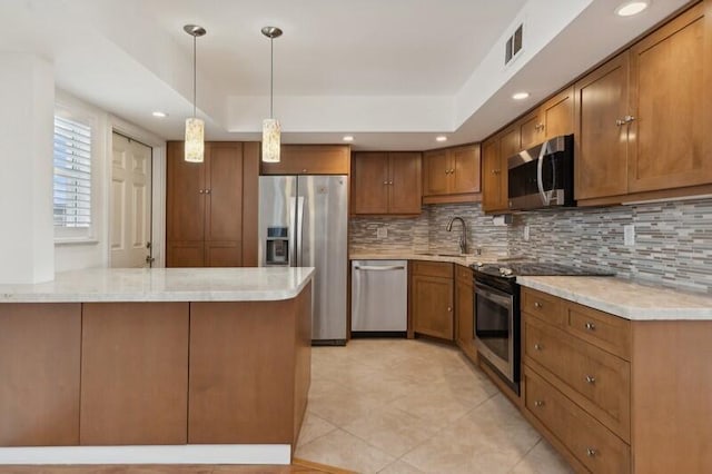 kitchen featuring appliances with stainless steel finishes, a tray ceiling, pendant lighting, and decorative backsplash