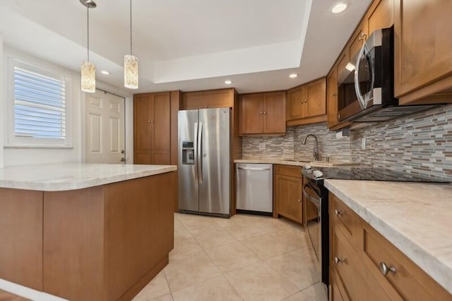 kitchen with hanging light fixtures, stainless steel appliances, a tray ceiling, and sink