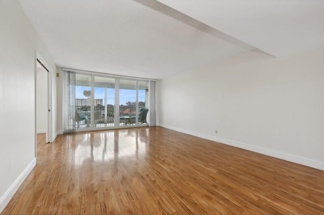 empty room with a wall of windows and light hardwood / wood-style floors