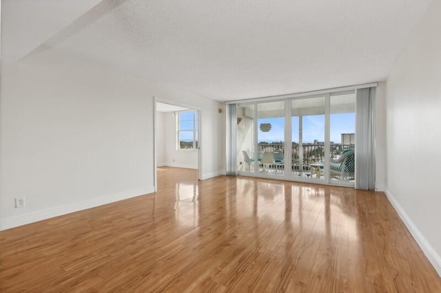 unfurnished living room with a wall of windows and light wood-type flooring