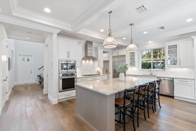 kitchen featuring wall chimney exhaust hood, hardwood / wood-style floors, stainless steel dishwasher, and a kitchen island