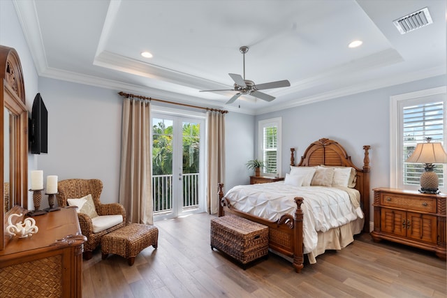 bedroom with a raised ceiling, access to exterior, light wood-type flooring, and ceiling fan