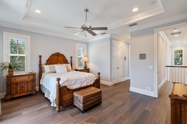 bedroom featuring ceiling fan, crown molding, dark hardwood / wood-style flooring, and a tray ceiling