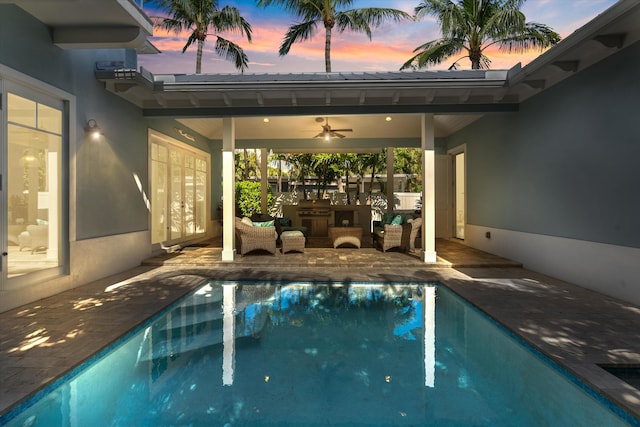 pool at dusk featuring ceiling fan and a patio area