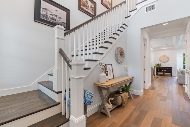 stairway featuring hardwood / wood-style flooring, beamed ceiling, and ornamental molding