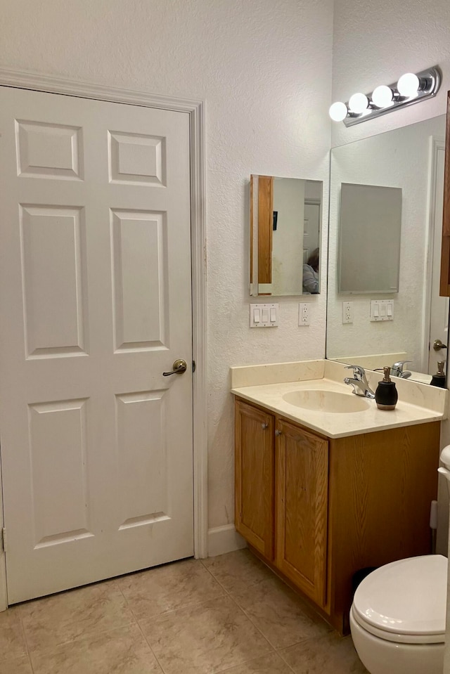 bathroom with toilet, tile patterned flooring, and vanity