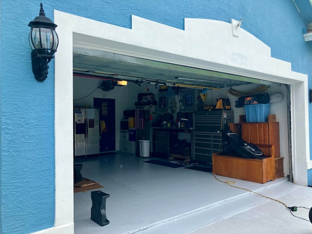 garage with stainless steel fridge and a garage door opener