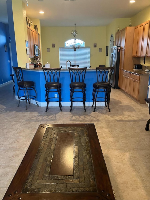 kitchen with hanging light fixtures, kitchen peninsula, a chandelier, appliances with stainless steel finishes, and a breakfast bar area