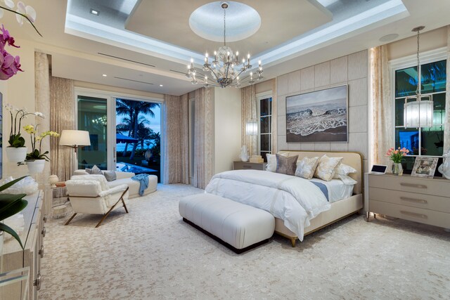 carpeted bedroom with a raised ceiling, a chandelier, and access to exterior