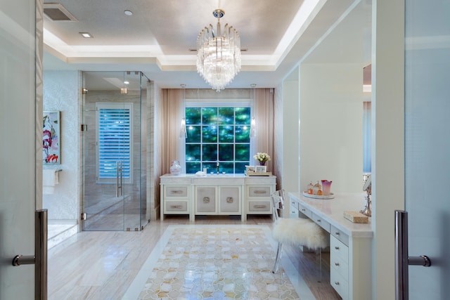 bathroom featuring vanity, a raised ceiling, an inviting chandelier, and an enclosed shower