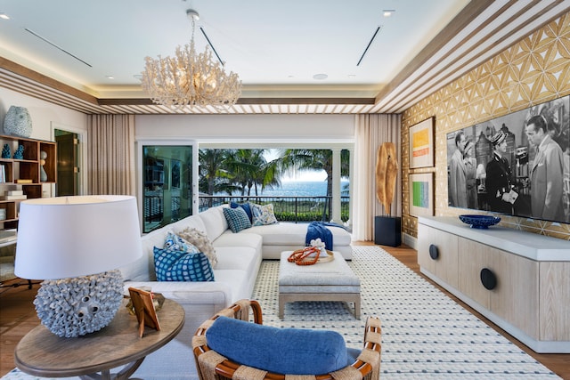 cinema with light hardwood / wood-style floors, an inviting chandelier, and a raised ceiling