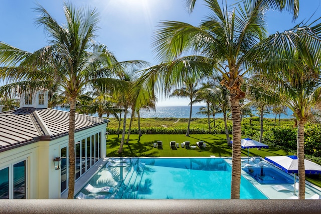 view of pool with a water view and a lawn