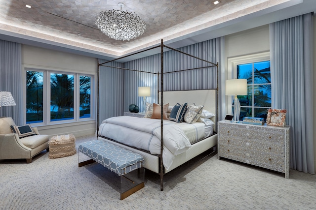 bedroom featuring carpet, a tray ceiling, and an inviting chandelier