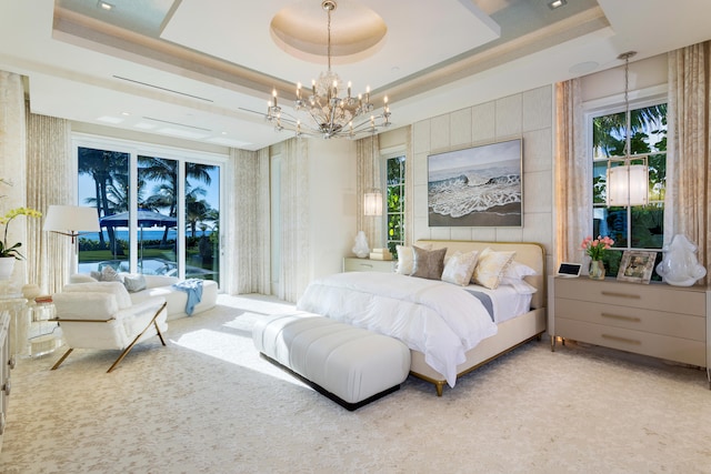 carpeted bedroom with a chandelier and a tray ceiling