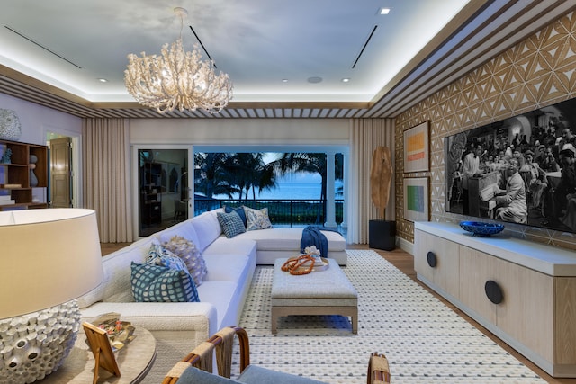 cinema with a chandelier, light hardwood / wood-style flooring, and a raised ceiling