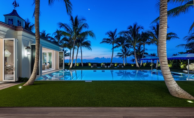 pool at dusk with a yard and a patio