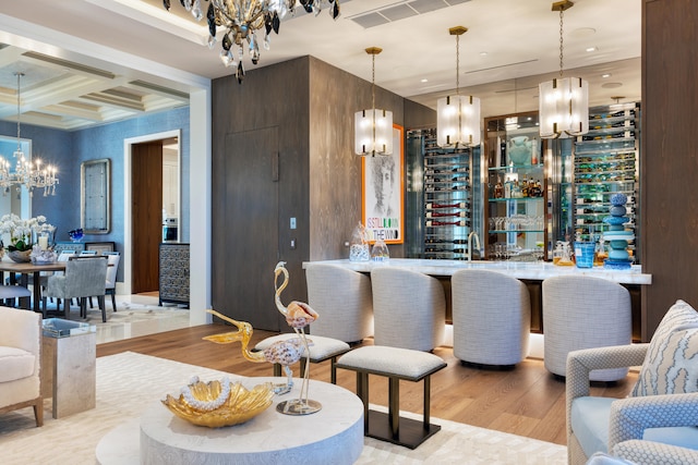 bar featuring beamed ceiling, light hardwood / wood-style flooring, coffered ceiling, and hanging light fixtures