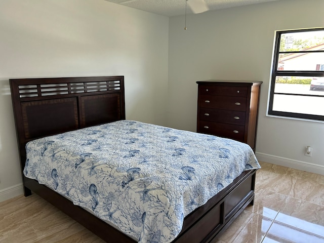 bedroom featuring ceiling fan, a textured ceiling, and light tile patterned floors