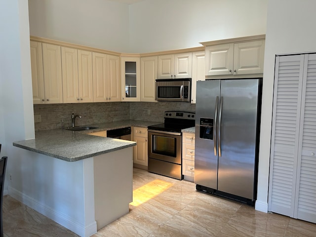 kitchen featuring stainless steel appliances, tasteful backsplash, sink, a high ceiling, and kitchen peninsula