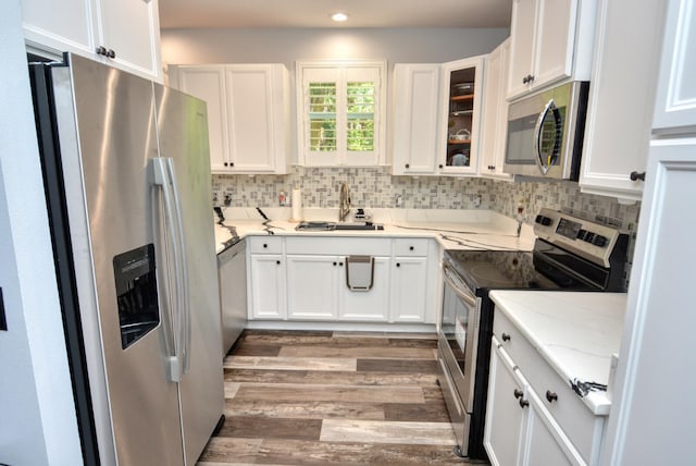 kitchen with light stone counters, stainless steel appliances, white cabinetry, and sink