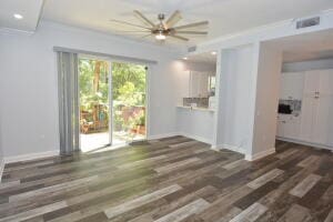 unfurnished living room featuring ceiling fan, dark hardwood / wood-style flooring, and crown molding