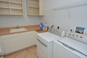 clothes washing area with separate washer and dryer and sink