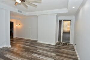 unfurnished room with dark hardwood / wood-style flooring, a raised ceiling, and ceiling fan