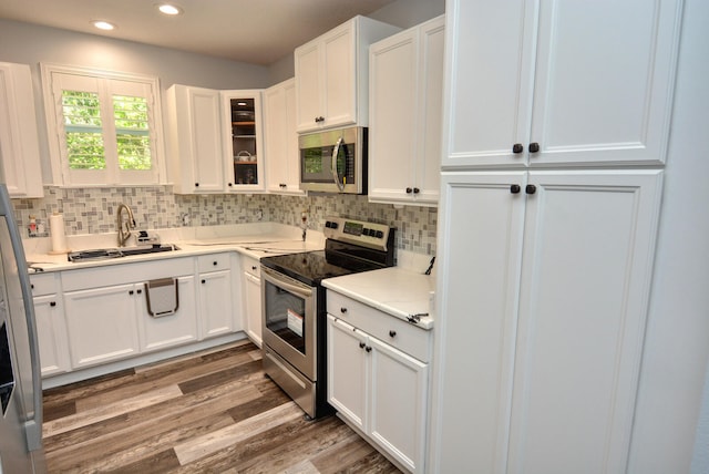 kitchen featuring tasteful backsplash, stainless steel appliances, sink, white cabinets, and hardwood / wood-style floors