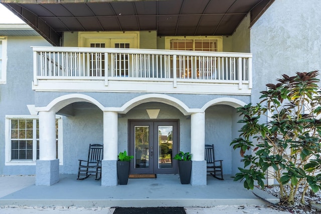 view of exterior entry featuring french doors and a balcony