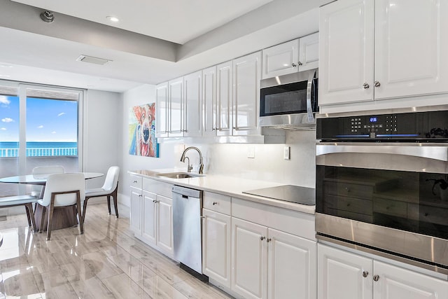 kitchen with stainless steel appliances, decorative backsplash, white cabinets, and sink