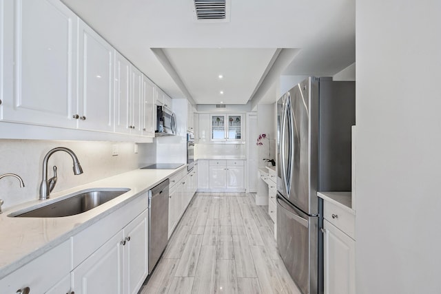 kitchen featuring tasteful backsplash, sink, light stone countertops, stainless steel appliances, and white cabinets