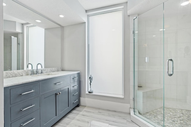 bathroom with a textured ceiling, an enclosed shower, and vanity