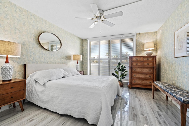 bedroom with ceiling fan, a wall of windows, a textured ceiling, and light hardwood / wood-style flooring