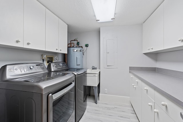 clothes washing area featuring water heater, separate washer and dryer, a textured ceiling, and cabinets