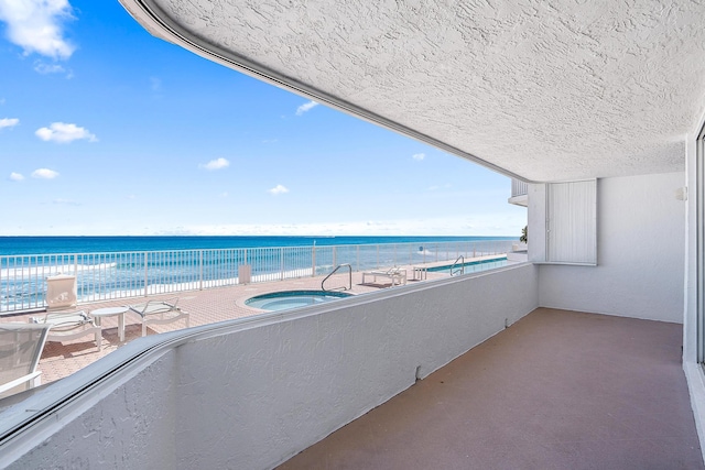 balcony with a water view and a hot tub