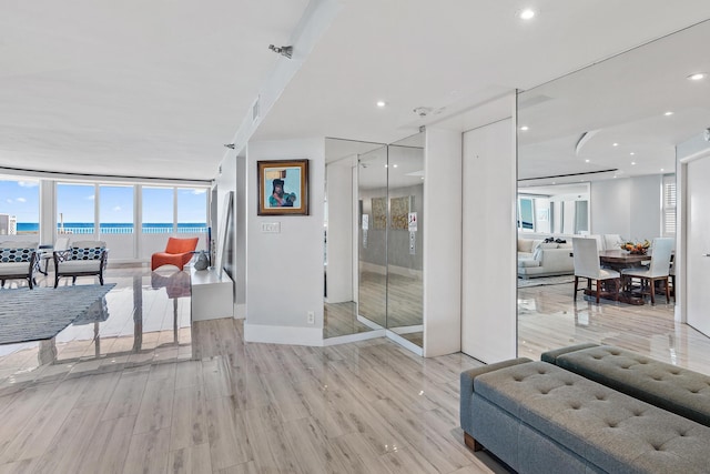 living room featuring expansive windows, a water view, and light wood-type flooring