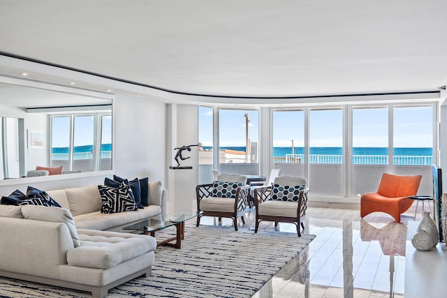 living room with light hardwood / wood-style floors, a water view, and a beach view