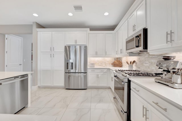 kitchen with decorative backsplash, appliances with stainless steel finishes, and white cabinets