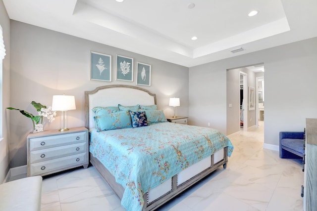 bedroom with ensuite bathroom and a raised ceiling