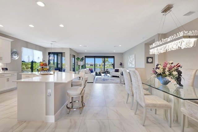 kitchen featuring white cabinetry, a breakfast bar area, decorative light fixtures, and a center island with sink