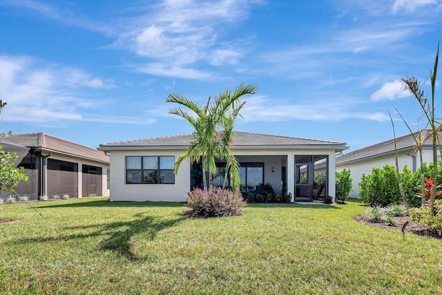 rear view of house featuring a yard and a sunroom