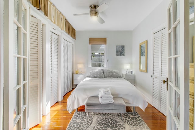 bedroom featuring light hardwood / wood-style flooring, two closets, and ceiling fan