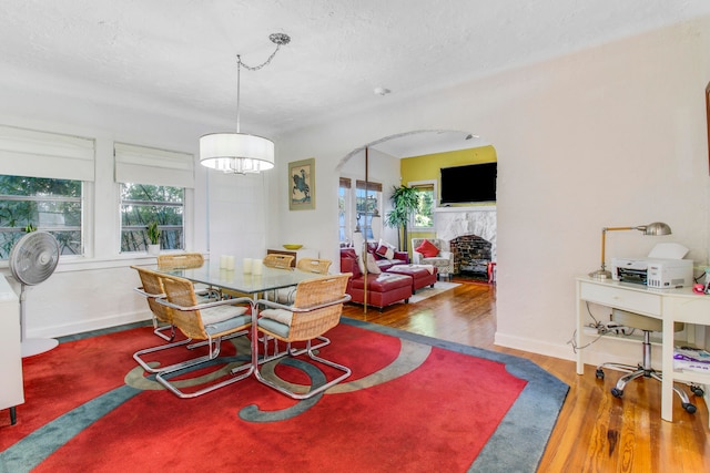 dining space featuring a textured ceiling, a fireplace, and wood-type flooring