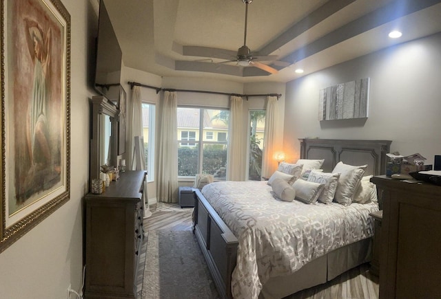 bedroom featuring ceiling fan, a raised ceiling, and dark hardwood / wood-style flooring