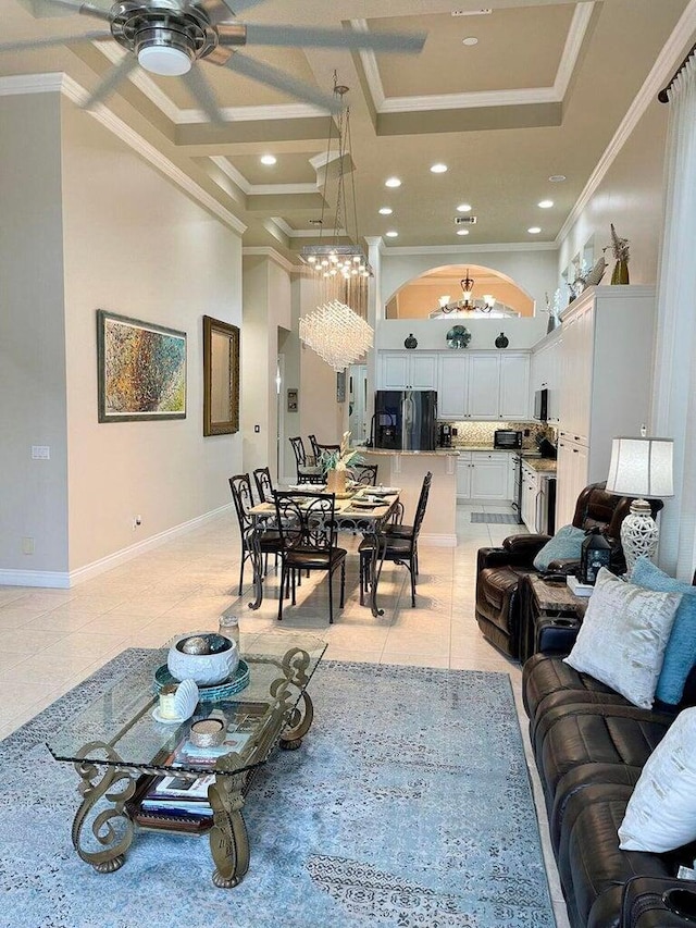 tiled living room with ceiling fan with notable chandelier and ornamental molding