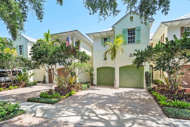 view of front of house with decorative driveway, an attached garage, and stucco siding